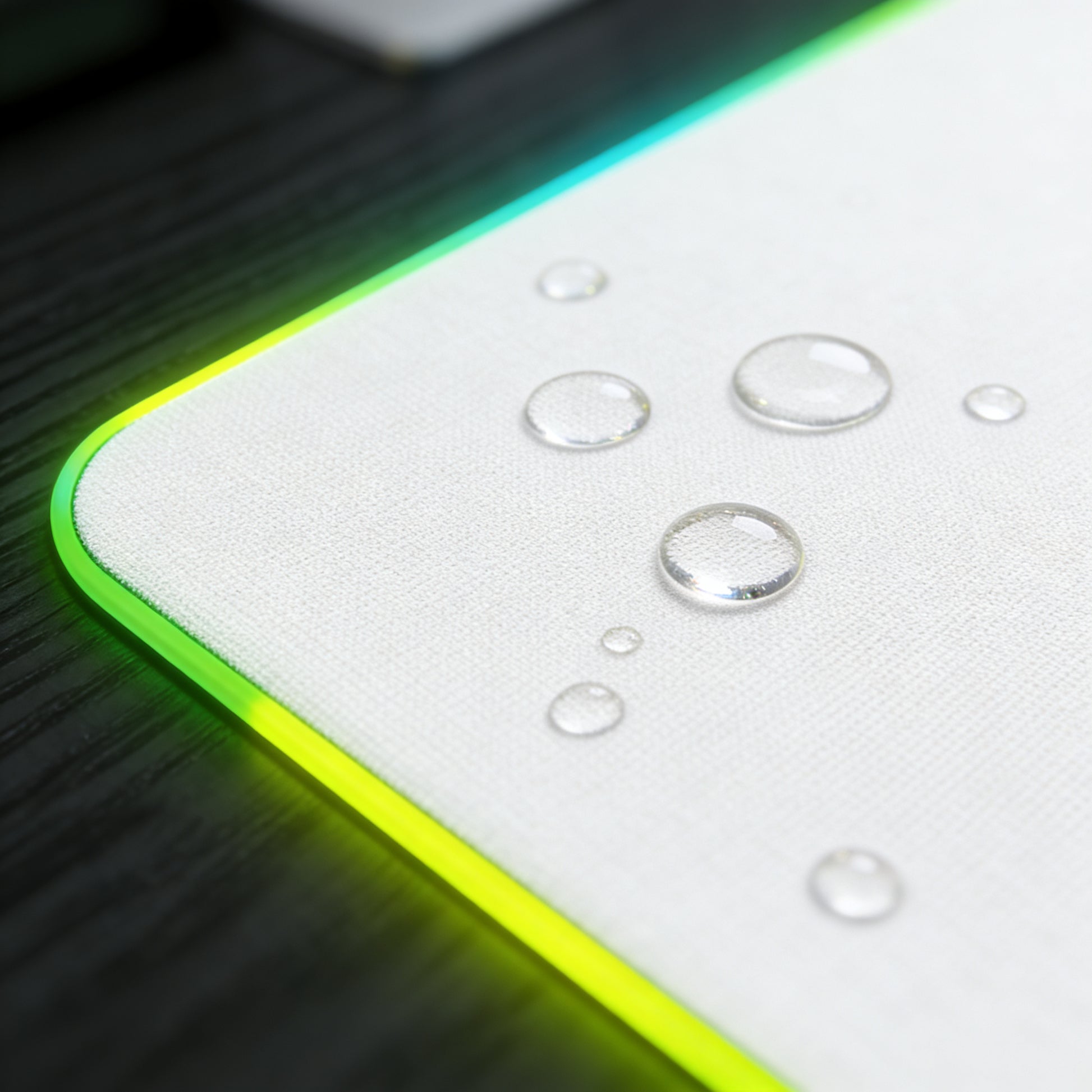 Close‑up of RGB mousepad surface with water droplets on the white cloth top, showing the water‑resistant and easy‑to‑clean coating.